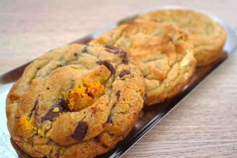 Cookies with chocolate chips and orange pieces on a metal tray.